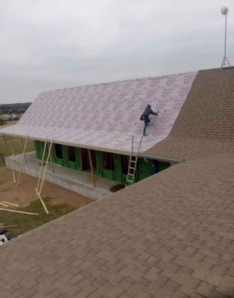 Worker preparing underlayment for a metal roof installation in Carver